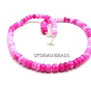May include: A necklace composed of pink and white beads, with a gradient effect from light to dark. The beads are strung together with a silver clasp. The text "SKGEMSNBEADS" is visible.