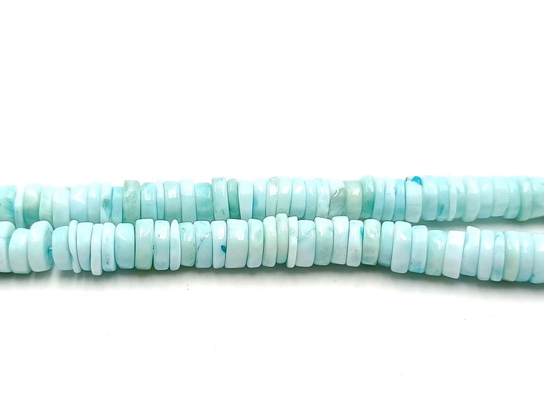 May include: Two strands of light blue, flat, round beads. The beads are a pale, seafoam color with subtle variations. The beads are strung together, creating a necklace or bracelet.