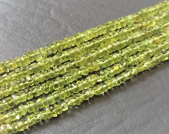 May include: A strand of light green peridot beads, each bead is faceted and has a square shape.