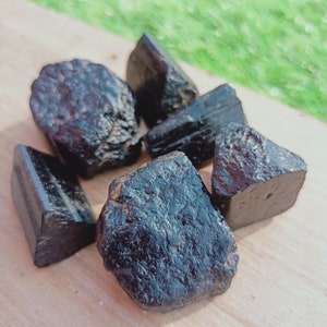 May include: A collection of six black obsidian stones of various shapes and sizes. The stones are smooth and polished, with a dark, glassy appearance.