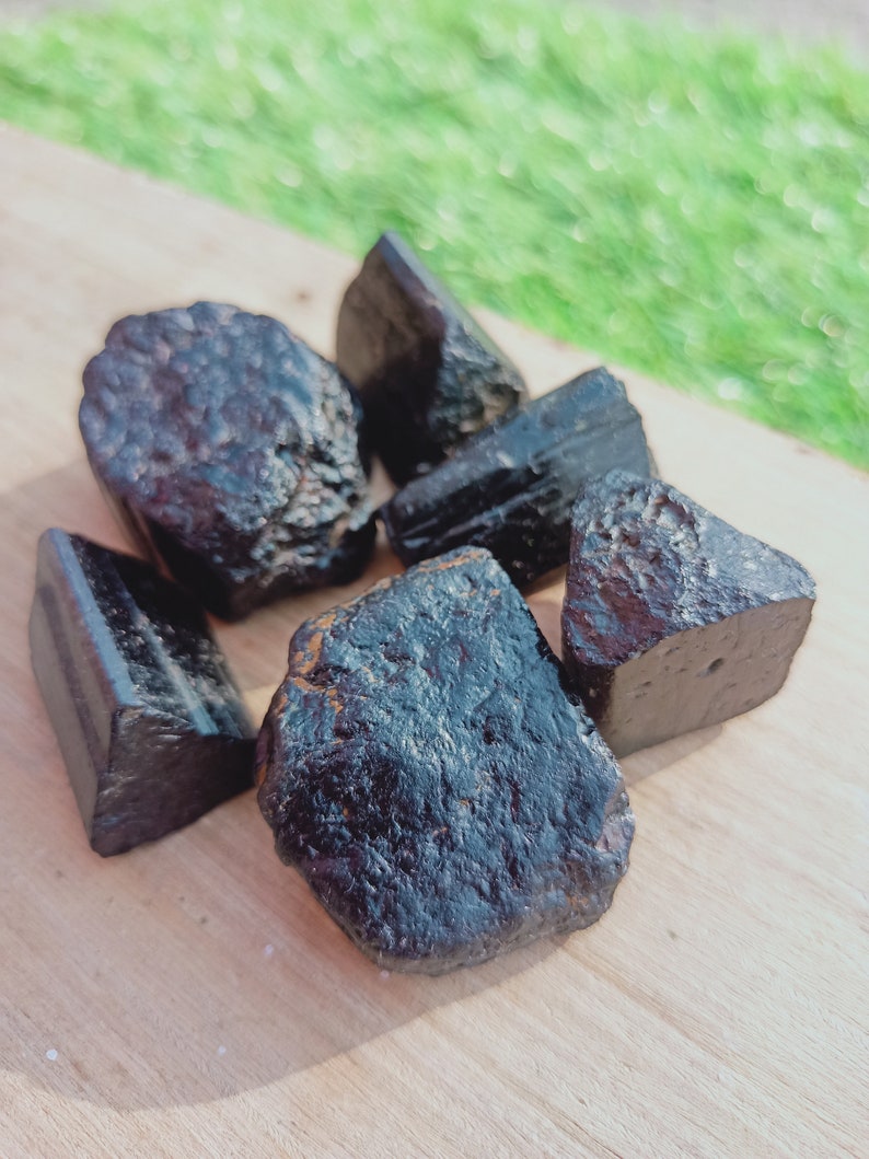 May include: A collection of six black obsidian stones of various shapes and sizes. The stones are smooth and polished, with a dark, glassy appearance.