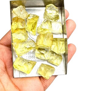 K&ouml;nnte beinhalten: Nahaufnahme eines kleinen Metalltabletts gef&uuml;llt mit gelben Citrin-Edelsteinen. Das Tablett liegt auf einer Hand.