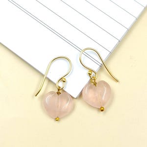 May include: A pair of gold heart-shaped earrings with pink rose quartz stones.
