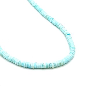 May include: A delicate necklace composed of small, round, light blue beads. The beads are uniform in size and shape, strung together to form a necklace. The necklace is set against a white background, highlighting the color and texture of the beads.