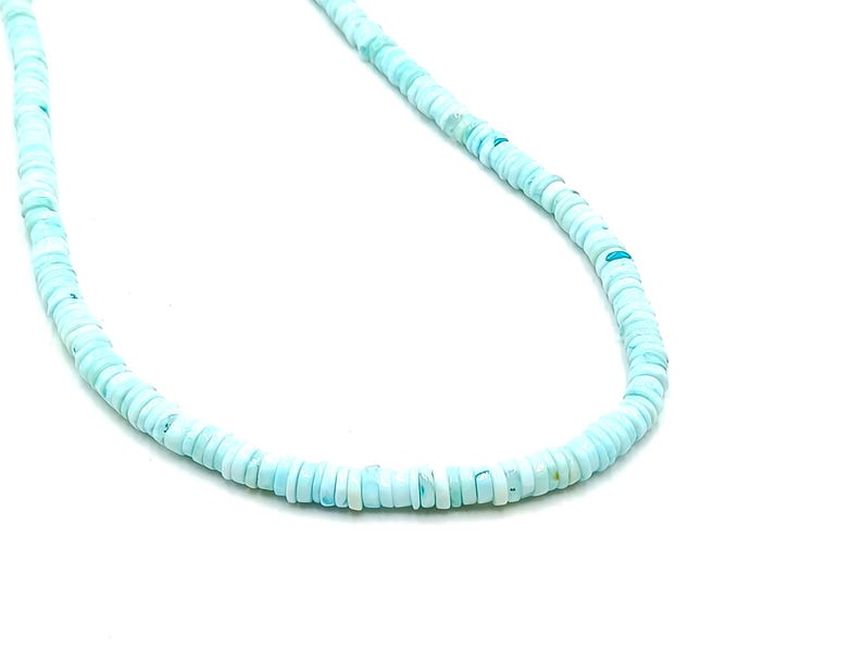 May include: A delicate necklace composed of small, round, light blue beads. The beads are uniform in size and shape, strung together to form a necklace. The necklace is set against a white background, highlighting the color and texture of the beads.