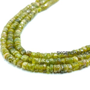 以下が含まれることがあります： 緑色の宝石ビーズのストランドで、ファセットカットされた正方形の形をしています。ビーズは透明な糸に通されており、層状のパターンで配置されています。ビーズは薄い緑色で、わずかに輝いています。