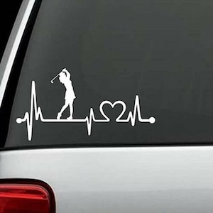 May include: White vinyl decal of a golfer silhouette with a golf club and a heart beat line with a heart in the middle.