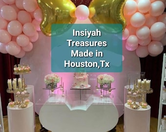 May include: A white Mickey Mouse-shaped table with a clear glass top. The table is decorated with pink and gold balloons, a cake, and other party decorations. The text "Insiyah Treasures Made in Houston, Tx" is visible on the table.