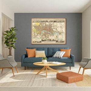 May include: A living room interior with a blue sofa, two gray chairs, a coffee table, and a large framed map of London on the wall. The room has a beige rug and a brown ottoman.