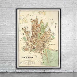 Könnte beinhalten: Eine antike Karte der Stadt Sydney, Australien, gedruckt in brauner, roter und grüner Tinte auf cremefarbenem Papier. Die Karte zeigt die Straßen, Parks und Wasserwege der Stadt. Der Titel "Map of the City of Sydney" ist unten auf der Karte gedruckt.