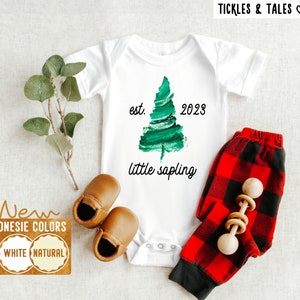 Könnte beinhalten: Weißer Strampler mit einem grünen Aquarell-Baumdesign und dem Text "est. 2023 little sapling".