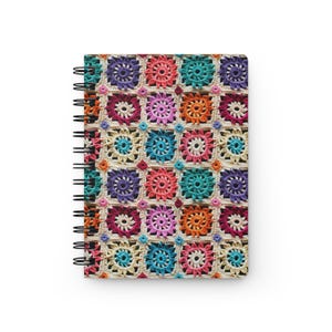 Pode incluir: Um caderno de espiral com uma capa de croch&ecirc; colorida. A capa apresenta um padr&atilde;o repetitivo de quadrados com fios de diferentes cores.