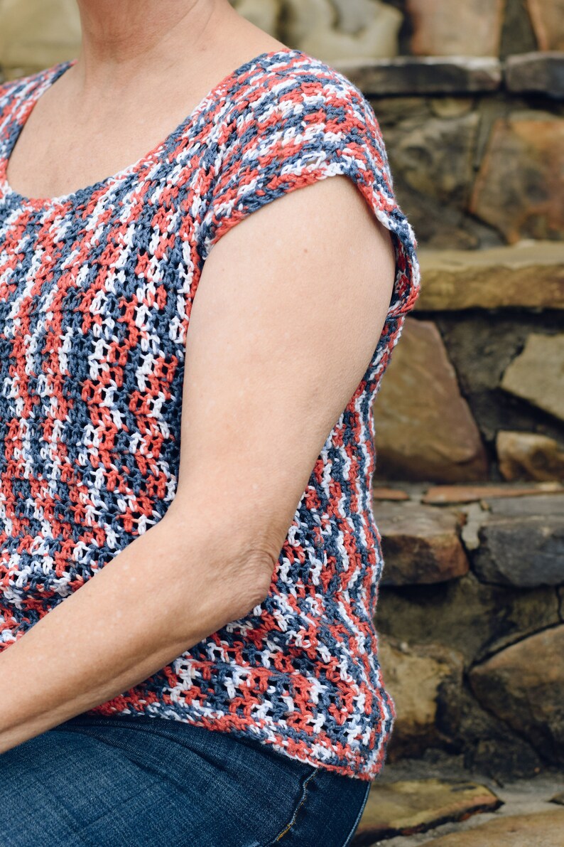 May include: A crocheted top with a striped pattern in shades of red, white, and blue. The top has short sleeves and a scoop neck.
