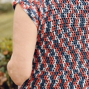 May include: A crocheted top with a striped pattern in shades of red, white, and blue. The top has short sleeves and a loose fit.