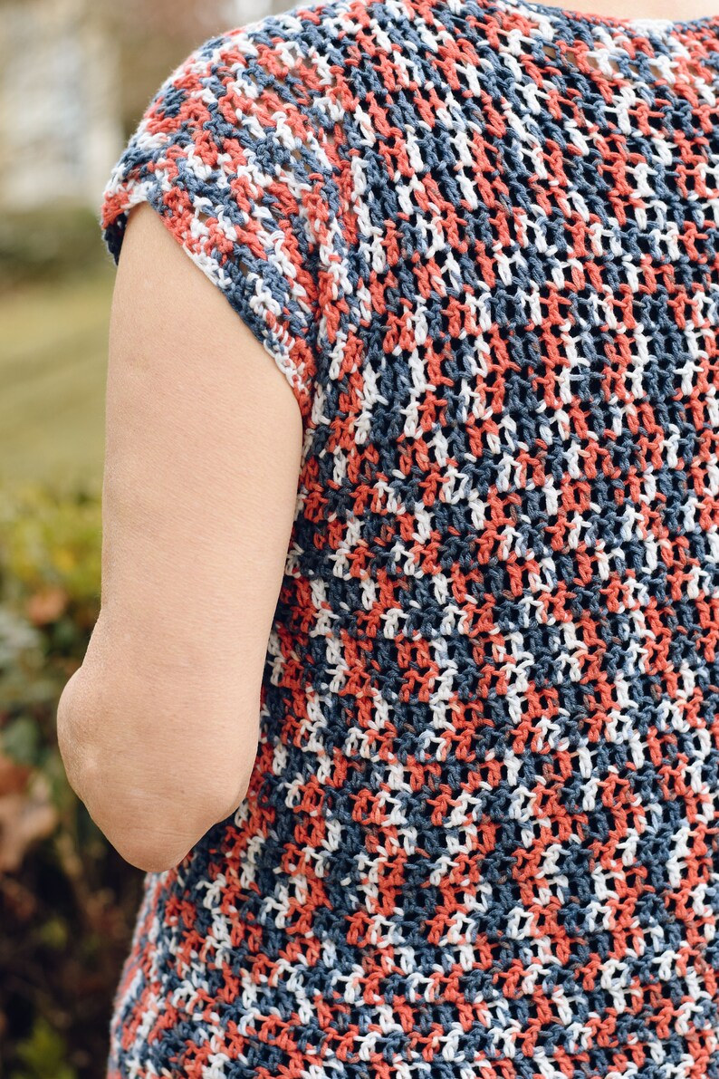 May include: A crocheted top with a striped pattern in shades of red, white, and blue. The top has short sleeves and a loose fit.