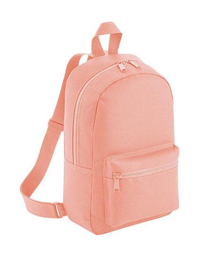 K&ouml;nnte beinhalten: Ein pfirsichfarbener Rucksack mit einem Hauptfach mit Doppelrei&szlig;verschluss, einer kleineren Vordertasche mit Rei&szlig;verschluss, einem Tragegriff an der Oberseite und verstellbaren Schultergurten aus passendem gewebtem Stoff.