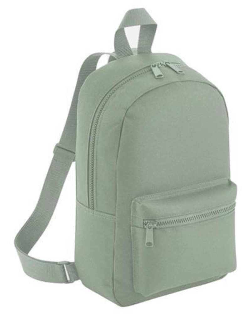 K&ouml;nnte beinhalten: Ein salbeigr&uuml;ner Rucksack mit einem Hauptfach mit zwei Rei&szlig;verschl&uuml;ssen, einer kleineren Rei&szlig;verschlusstasche auf der Vorderseite und verstellbaren Schultergurten. Der Rucksack hat einen Tragegriff oben und besteht aus einem glatten Stoff.