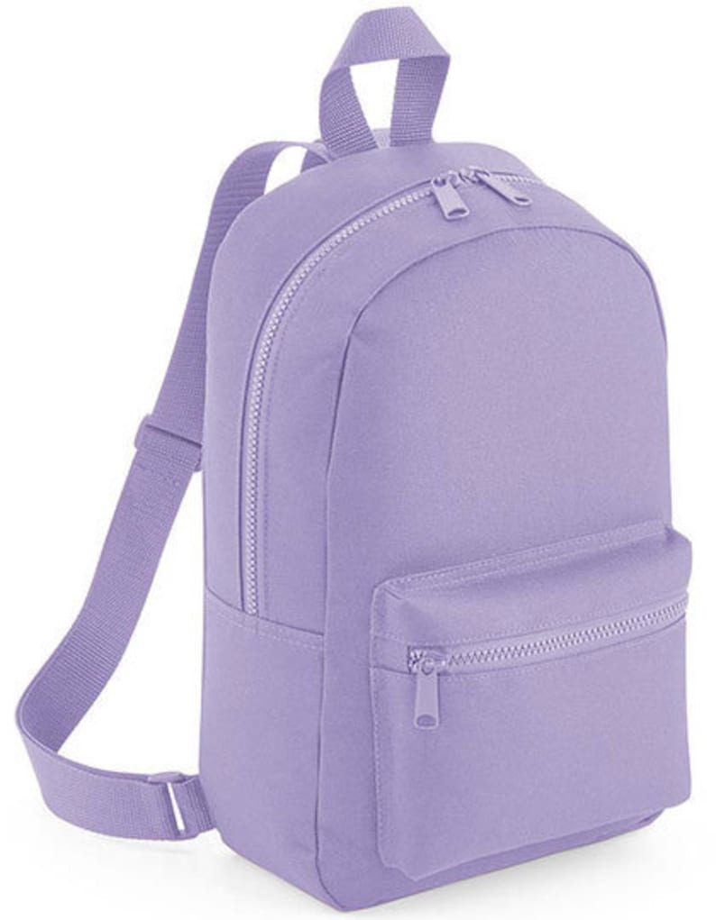 K&ouml;nnte beinhalten: Ein einfarbiger, hellvioletter Rucksack mit einem Hauptfach mit Rei&szlig;verschluss und einer kleineren Rei&szlig;verschlusstasche auf der Vorderseite. Der Rucksack verf&uuml;gt &uuml;ber verstellbare Schultergurte und einen Tragegriff, alles aus passendem lavendelfarbenem Stoff.