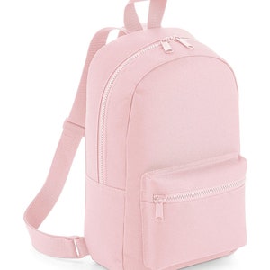 K&ouml;nnte beinhalten: Ein hellrosa Rucksack mit einem Hauptfach mit Rei&szlig;verschluss und einer kleineren Rei&szlig;verschlusstasche auf der Vorderseite. Der Rucksack verf&uuml;gt &uuml;ber verstellbare Schultergurte und einen Tragegriff an der Oberseite, alles aus passendem hellrosa Stoff mit silberfarbenen Rei&szlig;verschl&uuml;ssen.
