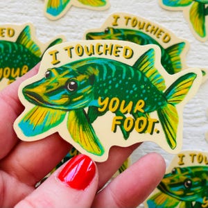 May include: A green and yellow fish sticker with the text "I touched your foot." The fish has a large mouth and is swimming to the right.