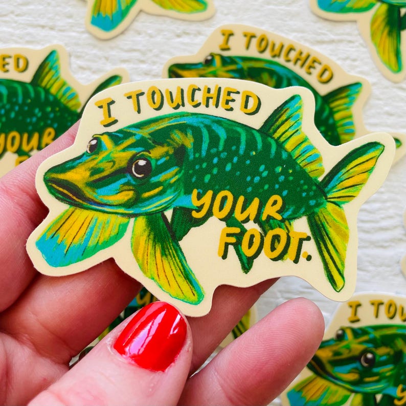 May include: A green and yellow fish sticker with the text "I touched your foot." The fish has a large mouth and is swimming to the right.