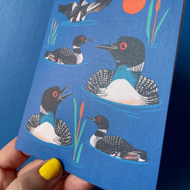 Pode incluir: Um fundo azul com um padr&atilde;o repetido de p&aacute;ssaros mergulhadores pretos e brancos nadando na &aacute;gua. Os p&aacute;ssaros t&ecirc;m olhos vermelhos e est&atilde;o virados em dire&ccedil;&otilde;es diferentes. Tamb&eacute;m h&aacute; juncos verdes e um sol vermelho no fundo.