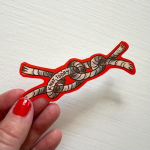 Peut inclure: Un autocollant découpé représentant une corde marron et beige nouée. La corde présente une bordure rouge vif et inclut le texte KNOT TODAY écrit en lettres capitales noires le long du centre du motif de la corde sur un fond blanc.