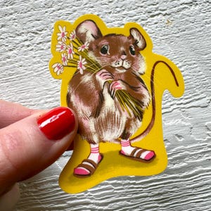 May include: A vintage-style sticker featuring a brown mouse holding a bouquet of white flowers. The mouse wears pink-striped socks and brown sandals with pink accents. The sticker has a yellow outline.