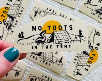 May include: A sticker with a black and white illustration of a skunk and a tent with the text "No Toots in the Tent". The background is a cream color with a yellow sun.