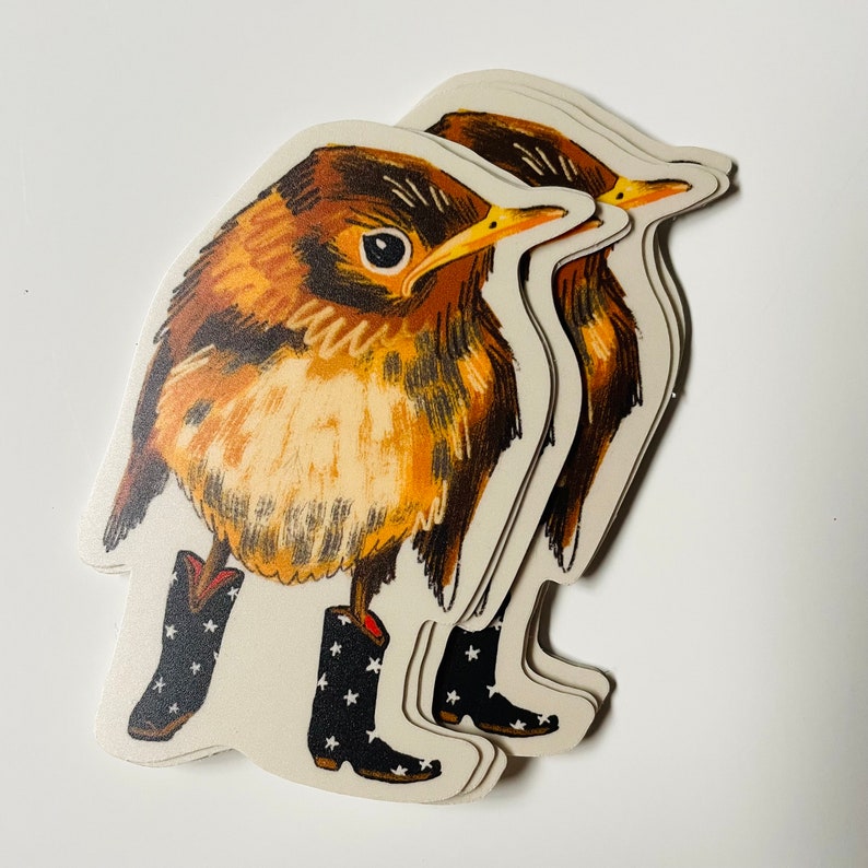 May include: Three brown and yellow bird stickers with black star-shaped boots. The birds are stacked on top of each other, with the top bird's head turned to the side.