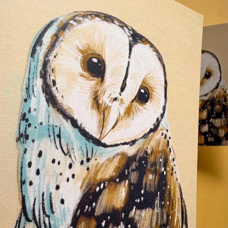 May include: A canvas print featuring a detailed illustration of a barn owl with a heart-shaped white face, large dark eyes, and brown and black speckled feathers. The owl is depicted against a light beige background with soft blue accents.