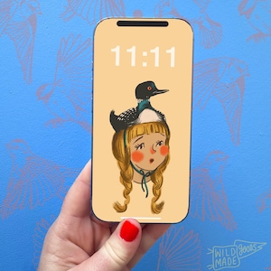 May include: A smartphone displaying a digital illustration on its screen. The screen shows the time 11:11 in white text above a drawing of a person with blonde braided hair wearing a loon bird as a hat on a light peach background.