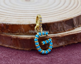 May include: Gold charm with the letter G, outlined with turquoise blue beads. The charm has a small loop at the top for attaching to a necklace or bracelet.