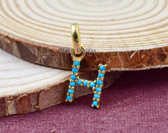 May include: Gold charm with the letter H, decorated with turquoise blue beads. The charm has a loop at the top for attaching to a necklace or bracelet.