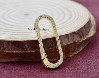 Pode incluir: Um amuleto oval de ouro com uma borda incrustada de diamantes. O amuleto está sobre uma superfície de madeira.