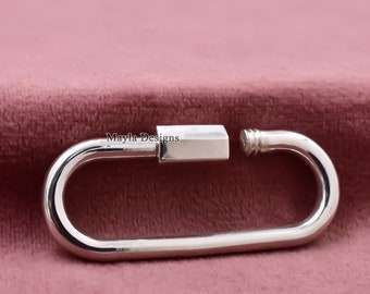 May include: A silver metal clasp with a screw closure. The clasp is oval shaped and has a smooth, polished finish.