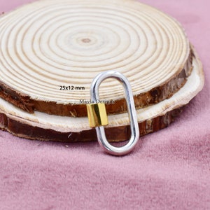 May include: Silver oval-shaped lobster clasp with a gold-colored barrel. The clasp measures 25x12 mm. The text "Mayla Designs" is visible on the clasp.