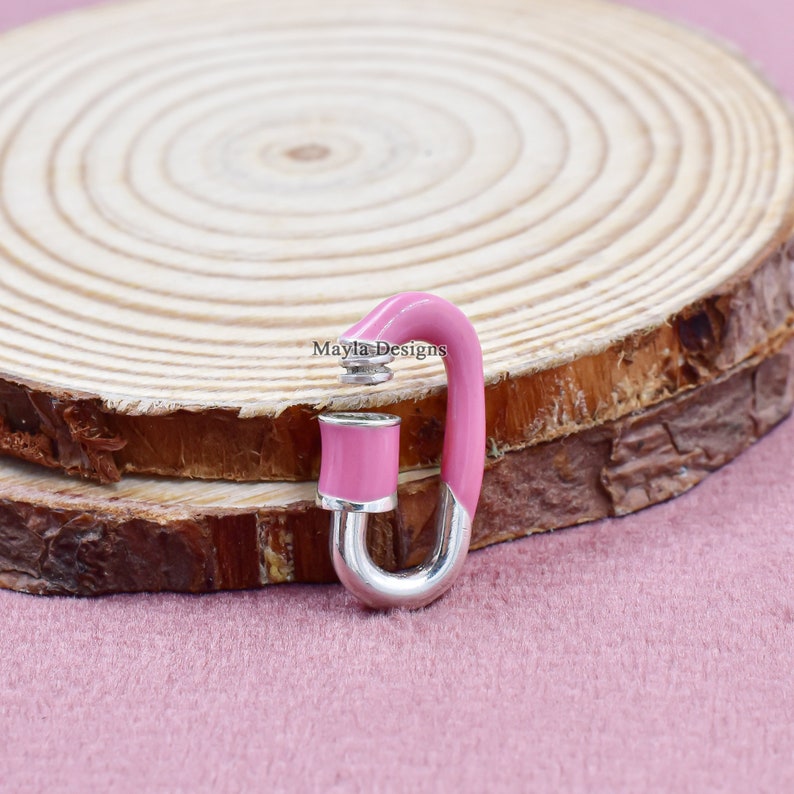 May include: A pink and silver metal clasp with a rounded shape. The clasp is enamelled in a bright pink color and has a silver metal loop.
