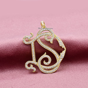 May include: Gold pendant necklace with a large, ornate letter 'S' design. The letter is encrusted with small, clear stones.