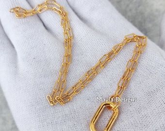 May include: Gold chain necklace with a gold oval clasp. The chain is made of small, linked rectangles. The necklace is on a white surface. Mayla Designs is written in the bottom right corner of the image.