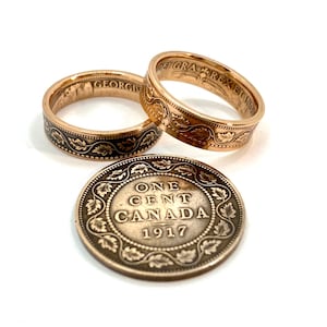 Op de afbeelding: Twee gouden ringen gemaakt van Canadese ééncentmunten uit 1917. De ringen dragen de tekst "ONE CENT CANADA 1917" en een bladontwerp. Een derde munt is te zien in het midden van de afbeelding.
