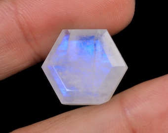 May include: A hexagonal, iridescent moonstone cabochon with a blue sheen. The stone is cut and polished to a smooth finish.