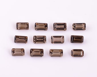 以下が含まれることがあります： 長方形のエメラルドカットの煙水晶の宝石が12個。宝石は3列4個ずつ、白い背景に並んでいます。