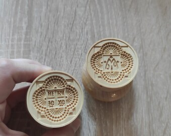 May include: Two wooden stamps with intricate designs. One stamp features a cross with the letters "IC XC" and the other features a "M" with a crown.