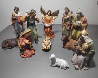 May include: A nativity scene figurine set with 10 figures, including Mary, Joseph, baby Jesus, an angel, three wise men, two sheep, and a donkey. The figures are made of painted resin and have a traditional Christmas theme.