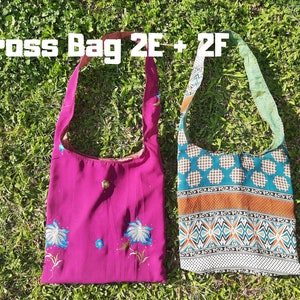 Pu&ograve; includere: Due borse a tracolla sono appoggiate sull'erba verde. Una &egrave; magenta con ricami floreali blu. L'altra &egrave; decorata con motivi geometrici turchese, arancione e bianchi. Il testo "Cross Bag 2E + 2F" &egrave; in alto.
