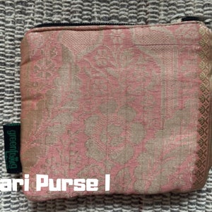 K&ouml;nnte beinhalten: Eine rosa und goldene Clutch aus Sari-Stoff mit einem Rei&szlig;verschluss und einem gr&uuml;nen "greenbag"-Etikett. Die Clutch ist mit einem Blumenmuster verziert. "Sari Purse I" steht unter der Clutch.
