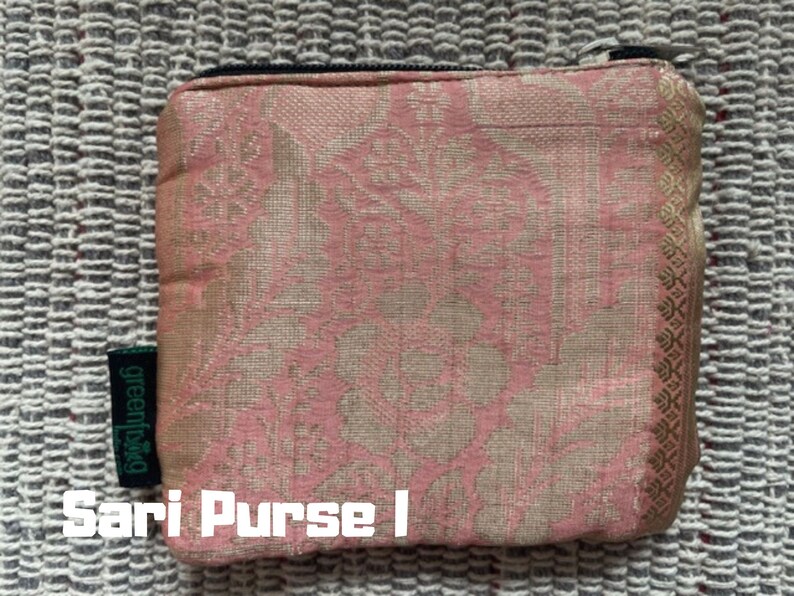 K&ouml;nnte beinhalten: Eine rosa und goldene Clutch aus Sari-Stoff mit einem Rei&szlig;verschluss und einem gr&uuml;nen "greenbag"-Etikett. Die Clutch ist mit einem Blumenmuster verziert. "Sari Purse I" steht unter der Clutch.