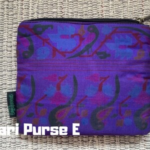 K&ouml;nnte beinhalten: Lila und schwarze gemusterte Stofftasche mit Rei&szlig;verschluss und dem Text "greenliving" an der Seite. Sari Purse E.