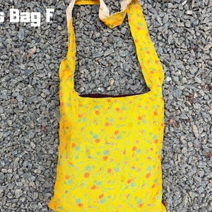 Pu&ograve; includere: Borsa a tracolla gialla con un motivo floreale arancione e blu. La borsa ha una lunga tracolla ed &egrave; realizzata in un tessuto leggero. Il testo "Cross Bag F" &egrave; visibile in alto.
